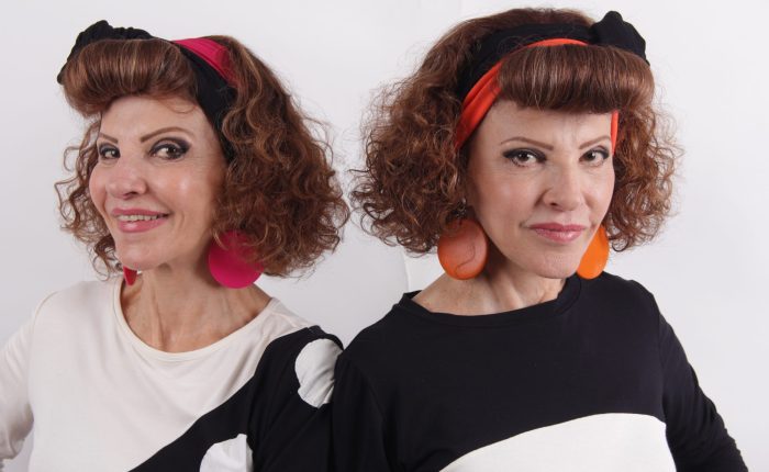 As gemeas Celia e Celma usando roupas preto e branco e com laço vermelho na cabeça.
